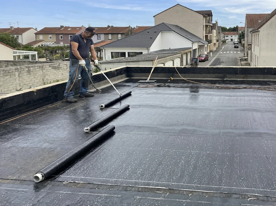 Ouvrier spécialisé en étanchéité appliquant une membrane bitumineuse sur une toiture-terrasse avec une raclette professionnelle, vue de près montrant le geste technique et le matériau d'étanchéité, en environnement de chantier sur une terrasse ou toiture accessible. Lumière naturelle, qualité photographique professionnelle.